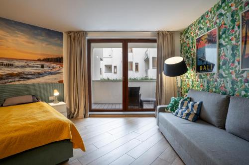 a bedroom with a bed and a couch and a window at Velapart in Władysławowo