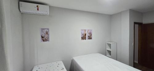 a white room with a bed and three pictures on the wall at Apartamento Barra Vento 2 in Guriri
