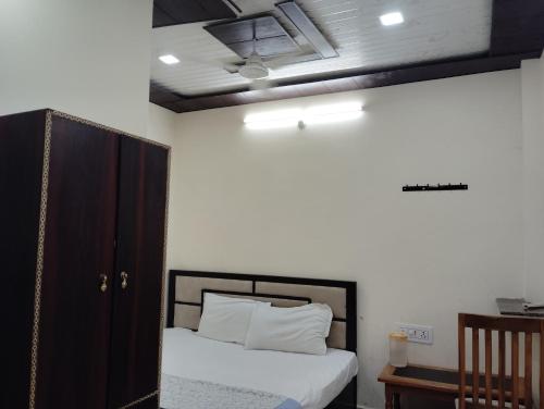 een slaapkamer met een bed met witte lakens en een plafond bij Maa tulsi guest house in Ayodhya