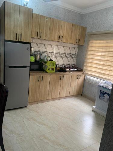 een keuken met een witte koelkast en houten kasten bij ELLEX SLEEVES APARTMENTs in Ibadan
