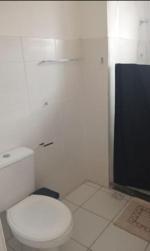a white bathroom with a toilet and a television at AP aconchego de Ilhéus in Ilhéus