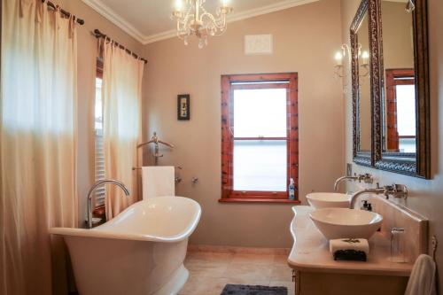 Un baño con tres lavabos y un espejo grande. en La Pension Guest House, en Oudtshoorn