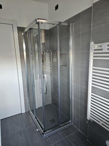 a glass shower in a bathroom with gray tiles at Luca Apartment Rho in Rho