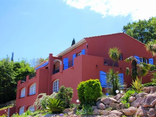 a red house with blue windows on a hill at Le Mas de la Verrerie in Les Adrets de l'Esterel