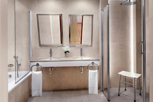 ein Badezimmer mit einem Waschbecken, zwei Spiegeln und einem Hocker in der Unterkunft Marriott’s Club Son Antem in Llucmajor