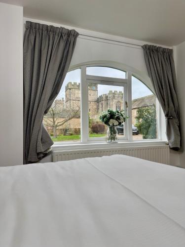 a bedroom with a bed and a window with a vase of flowers at Castle View Cottage at Snape Castle Mews in Bedale