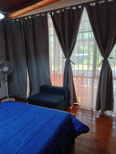 a bedroom with a blue bed and a chair and windows at ALOJAMIENTO SERRANO in Villa Giardino