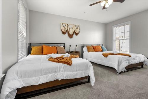 2 Betten in einem Schlafzimmer mit Weiß- und Orangetönen in der Unterkunft Home in National Harbor Area in Accokeek