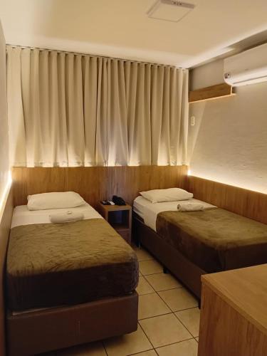 a hotel room with two beds and a window at Ipê Hotel Curitiba - Av das Torres in Curitiba