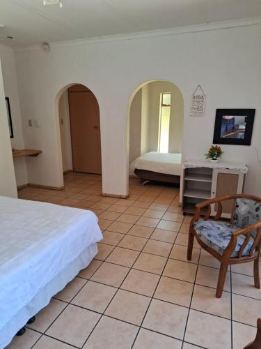 Casablanca Guesthouse في Carletonville: غرفة نوم بها سرير وكرسي وطاولة