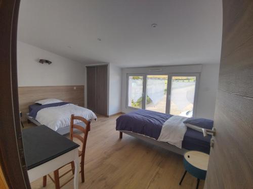 a bedroom with two beds and a desk and a window at Gîte Pink House in Rainville
