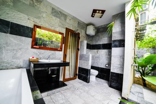 a bathroom with a sink and a tub and a toilet at Villa Orchid Garden Riverside Hoi An in Hoi An