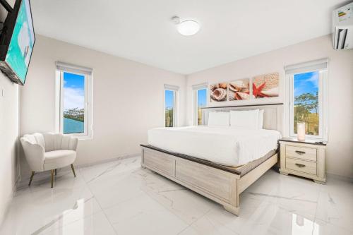ein Schlafzimmer mit einem Bett und einem Stuhl und Fenstern in der Unterkunft Monserat 33Q in Palm-Eagle Beach