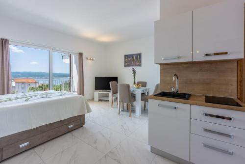 ein Schlafzimmer mit Bett und eine Küche mit Tisch in der Unterkunft Apartments Sunshine D in Crikvenica