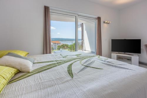ein Schlafzimmer mit einem großen Bett mit einem großen Fenster in der Unterkunft Apartments Sunshine D in Crikvenica