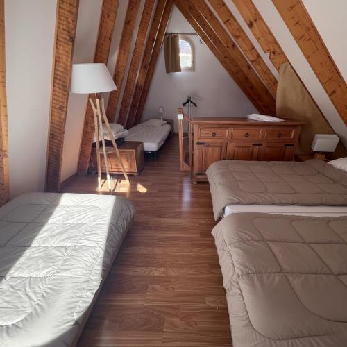 une chambre mansardée avec deux lits et un bureau dans l'établissement Chalet Pointu, à Isola 2000