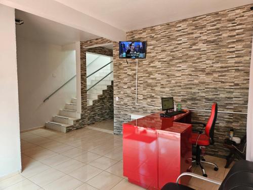 an office with a red desk and a tv on a brick wall at Suite Campina - Business Hotel in Campina do Monte Alegre