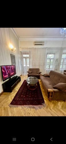 un salon avec un canapé et une télévision dans l'établissement Günlük evlər, à Baku