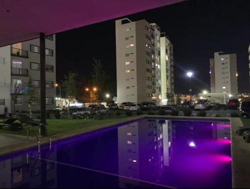 a swimming pool with purple lights in a city at night at Chalet Saint Lawrence GDL in Guadalajara