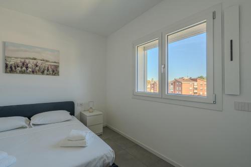 a white bedroom with a bed and a window at Casa Dalia in Garbagnate Milanese