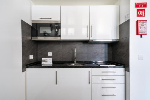 een keuken met witte kasten en een spoelbak bij SUITEON7TH VILAMOURA THE BEST VIEW IN TOWN - 1Br in Quarteira