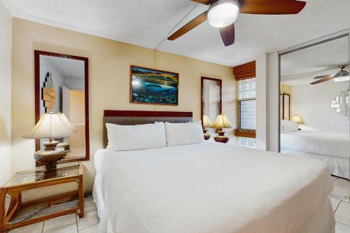 a bedroom with a large white bed with a ceiling fan at Island Sands Resort 103 in Maalaea