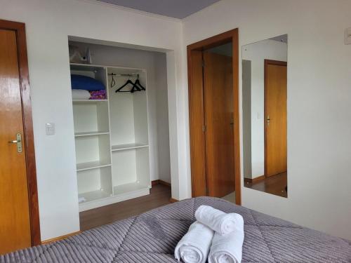 a bedroom with a bed with towels on it at Casa vista das colinas in Gramado