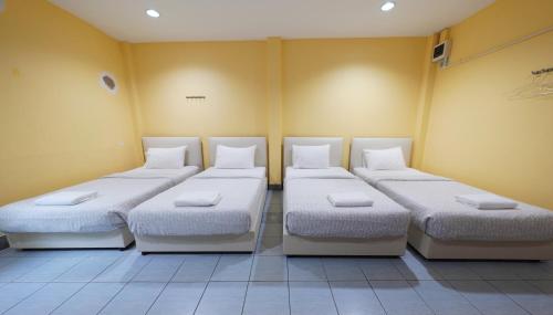 três camas num quarto com paredes amarelas em Excel Hotel Bangkok former Sri Krungthep Hotel em Banguecoque