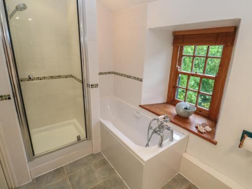 een badkamer met een bad, een douche en een wastafel bij 1 Rowes Cottages in Porthcurno