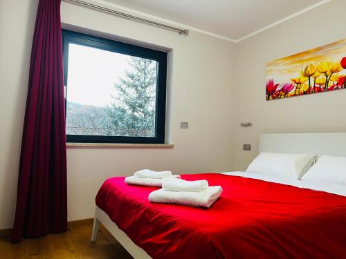 Un dormitorio con una cama roja con toallas. en La Rose du Prevot, en Fenis