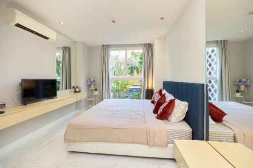 a bedroom with two beds and a flat screen tv at Pattaya Jomtien Apartments l Guest Friendly l Waterpark Gym Sauna Jacuzzi in Pattaya South