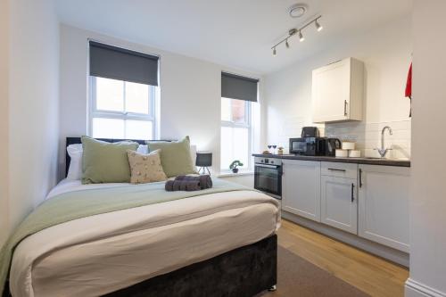 a bedroom with a large bed and a kitchen at St James Court Aparthotel in Derby