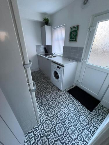 a laundry room with a washing machine and a door at Spacious 3-Bedroom Apartment with Modern Comforts in Runcorn