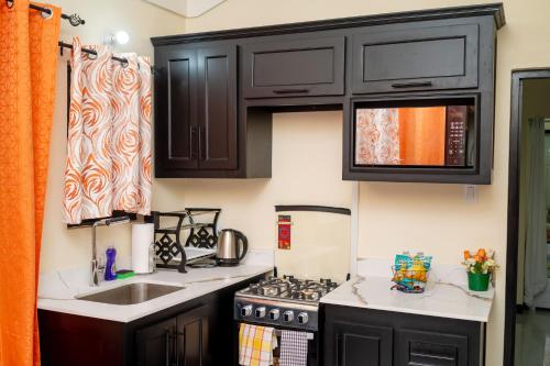 a kitchen with black cabinets and a stove at Dowayne 1bed 1 bath in gated community colbeck manor in Old Harbour