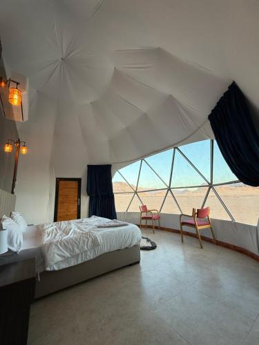 ワディ・ラムにあるWADI RUM STAR LOTE LUXURY CAMp & BUBBLES ROOMのベッドと大きな窓のある寝室