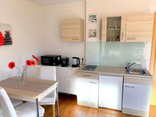 a kitchen with white cabinets and a table with a vase of flowers at Apartment Muehlbach by Interhome in Fliess