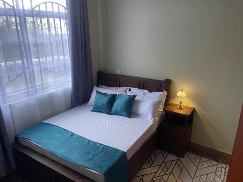 a bedroom with a bed with blue pillows and a window at Famurest in Nkoanrua