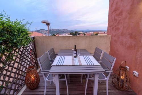 a table with chairs and a bottle of wine on a balcony at Loft Kala Zèna in La Maddalena