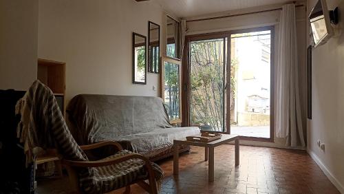 ein Wohnzimmer mit einer Couch und einem Tisch und einem Fenster in der Unterkunft Studio privé - maison de village in Valensole