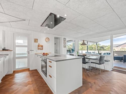 a kitchen with white cabinets and a table with chairs at Holiday Home Bela - from the sea by Interhome in Ringkøbing