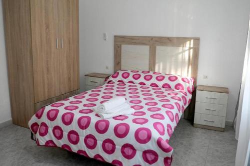 卡沃内拉斯Apartalux Luna Carboneras的卧室里铺着粉白相间的床罩，上面有粉色波点。