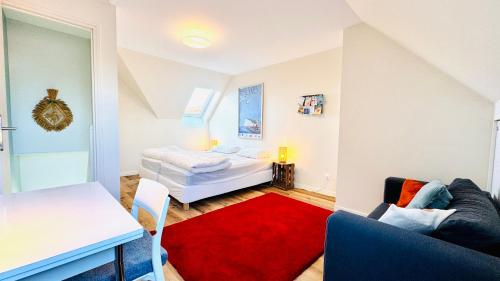 a living room with a bed and a red rug at Vue d'Opale - Appartement vue mer Stella-Plage in Stella-Plage