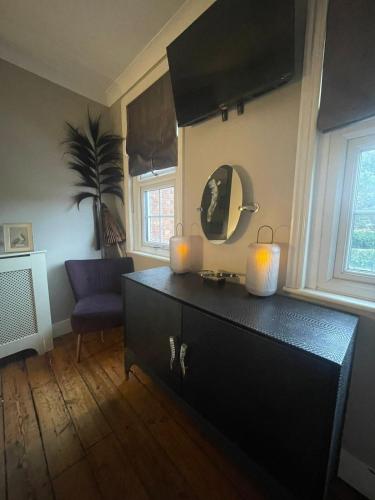 a room with a dresser with two candles and a mirror at The Little Boutique House in Byfleet