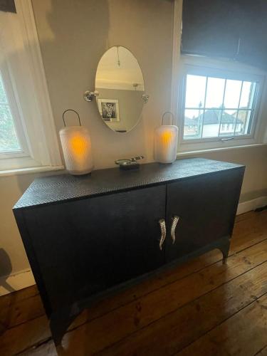 a black dresser with two candles and a mirror at The Little Boutique House in Byfleet