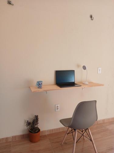 ein Laptop auf einem Regal an einer Wand mit einem Stuhl in der Unterkunft Koral House - GURIÚ in Camocim