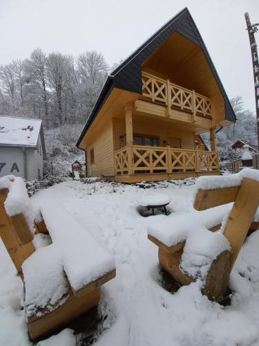 a log cabin in the snow with benches in front at Domek Sol Wilcza Zagroda in Kudowa-Zdrój