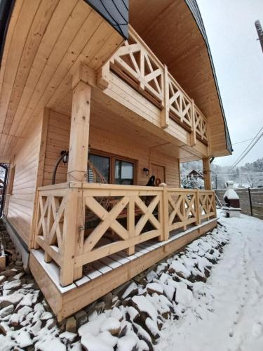 a log cabin in the snow with a porch at Domek Sol Wilcza Zagroda in Kudowa-Zdrój