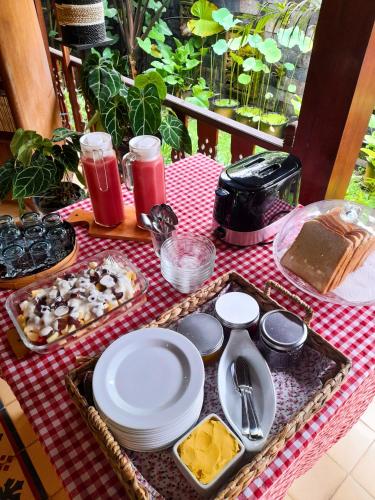 een tafel met borden en schalen op een rood geblokt tafelkleed bij Niti Bhumi Villa in Borobudur