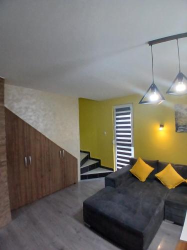 a living room with a black couch and yellow pillows at Apartman Romana Duplex Divčibare in Divčibare
