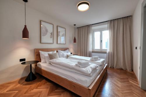 Steirerblicke City Apartments في غراتس: غرفة نوم بسرير كبير مع ملاءات بيضاء